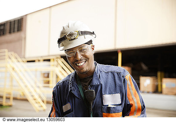 Happy male worker standing against recycling center