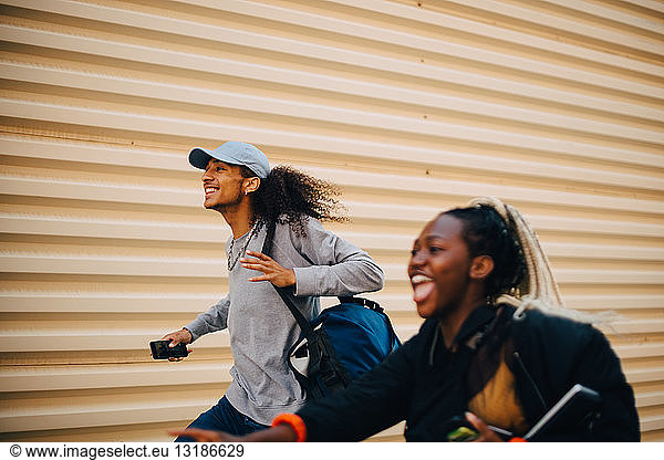 Happy man and teenage girl running by shutter