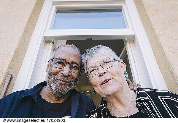 Happy man and woman against doorway in balcony
