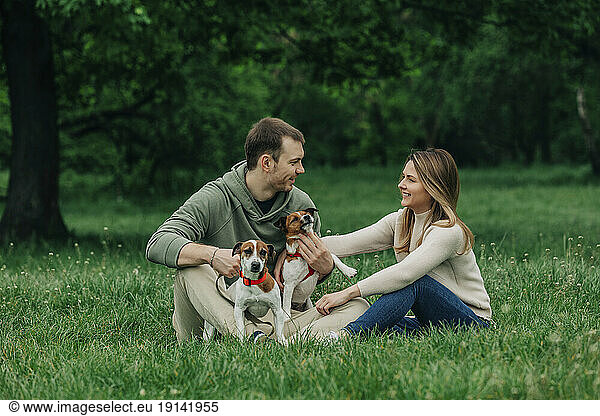 Happy man and woman enjoying with Jack Russell Terrier dogs in park