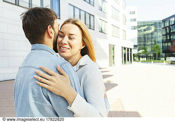 Happy man and woman hugging each other on sunny day