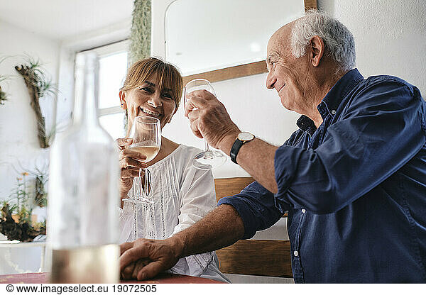 Happy man and woman sitting with glasses of wine in cafe
