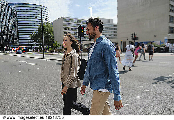 Happy man and woman walking together on street in city
