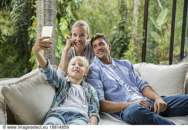Happy man and woman with boy taking selfie through smart phone