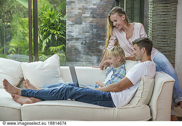 Happy man and woman with son using laptop at home