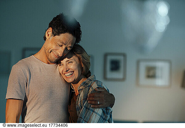 Happy man embracing cheerful woman at home