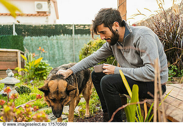 happy man enjoying tea with the dog in the garden