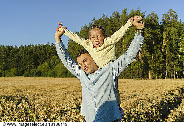 Happy man enjoying with playful daughter in field