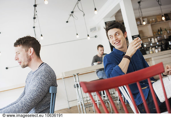 Happy man holding coffee cup while sitting at cafeteria