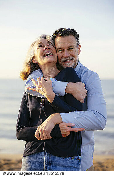Happy man hugging cheerful mature woman at beach