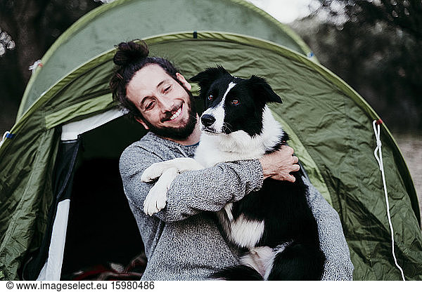 Happy man hugging his dog at a tent