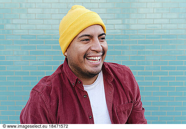 Happy man in front of turquoise brick wall