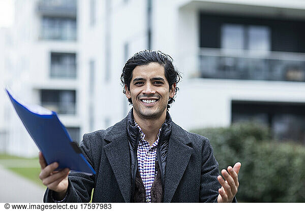 Happy man in warm clothing holding blue file