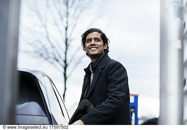 Happy man in warm clothing standing by car