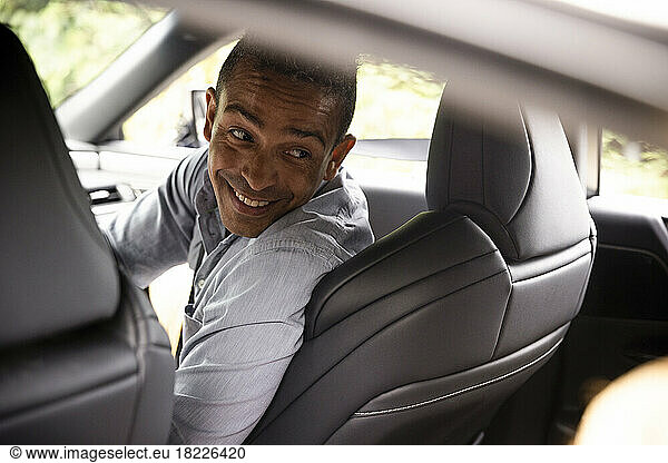 Happy man looking back over shoulder while sitting in car