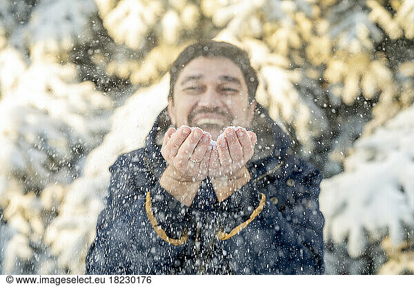 Happy man playing with snow in winter