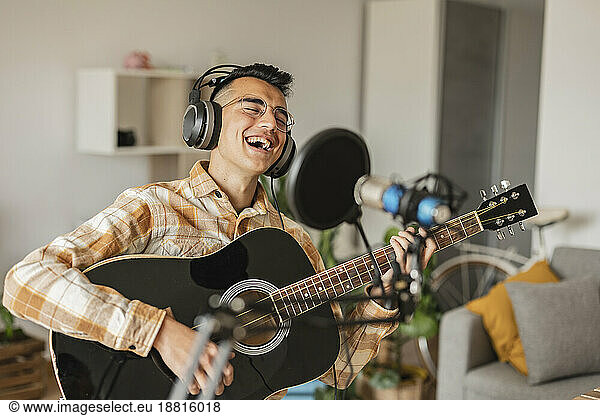 Happy man singing and playing guitar at home