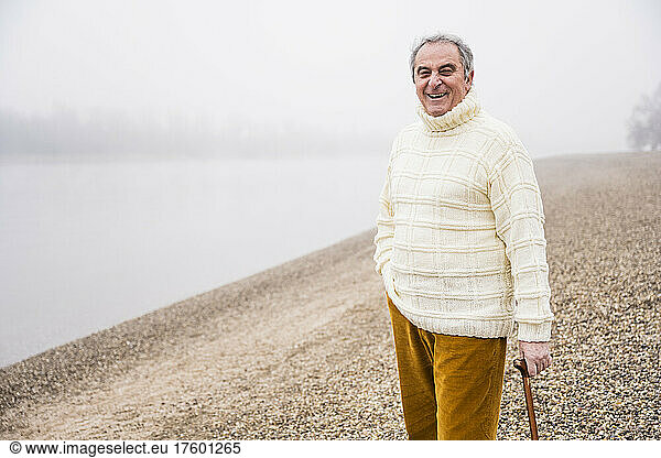 Happy man standing with hand in pocket at beach
