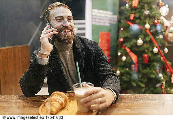 Happy man talking on mobile phone at restaurant