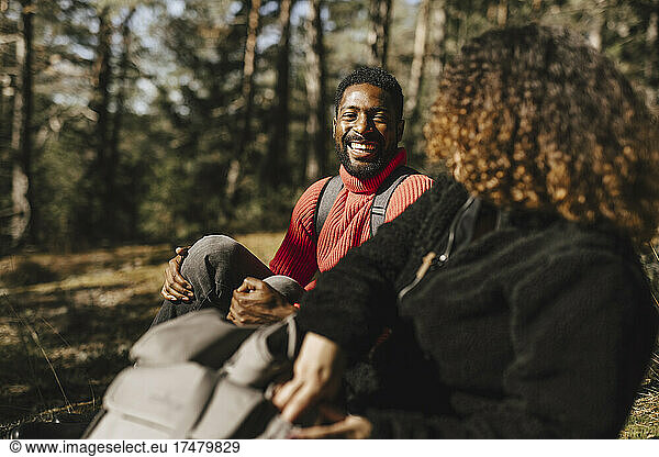 Happy man talking with girlfriend in forest during vacation