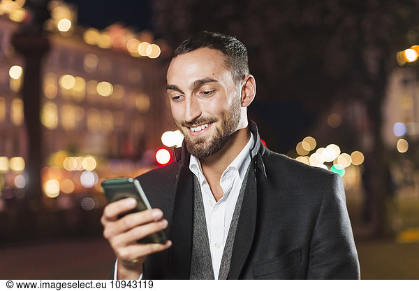 Happy man using smart phone in city at night