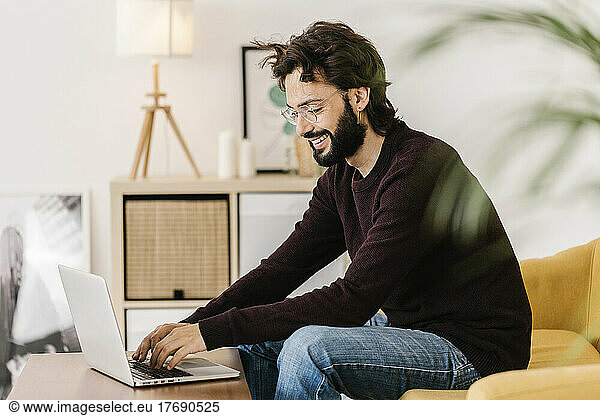 Happy man wearing eyeglasses using laptop at home
