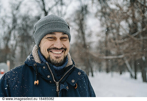 Happy man wearing knit hat enjoying snowfall
