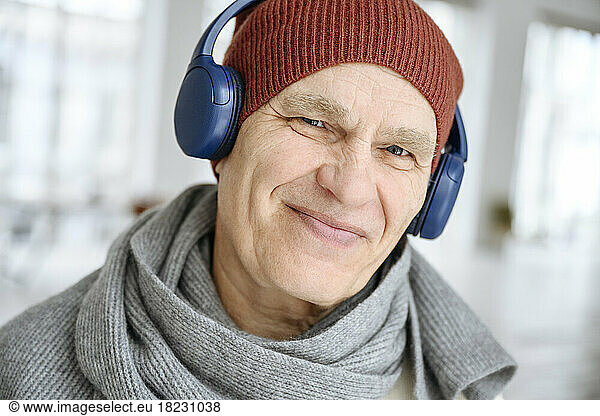 Happy man wearing knit hat listening to music through headphones