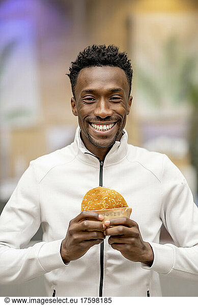 Happy man with black hair holding burger