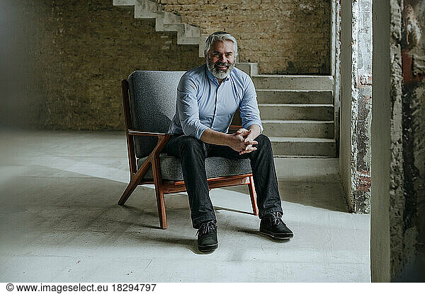 Happy mature architect sitting in chair at construction site
