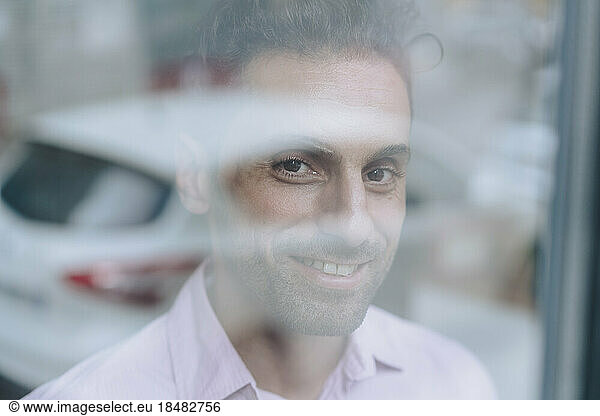 Happy mature businessman seen through glass