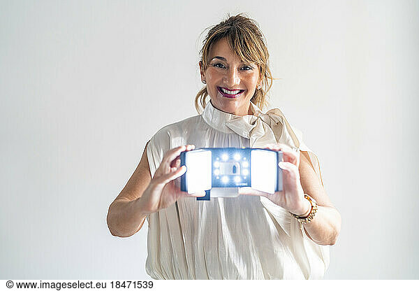 Happy mature businesswoman showing magnification equipment against white background