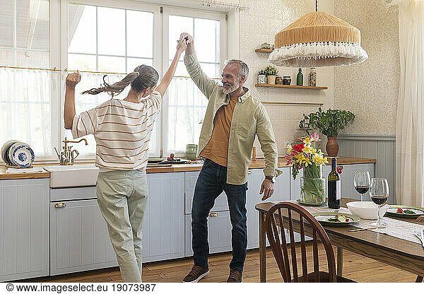 Happy mature couple dancing in kitchen at home
