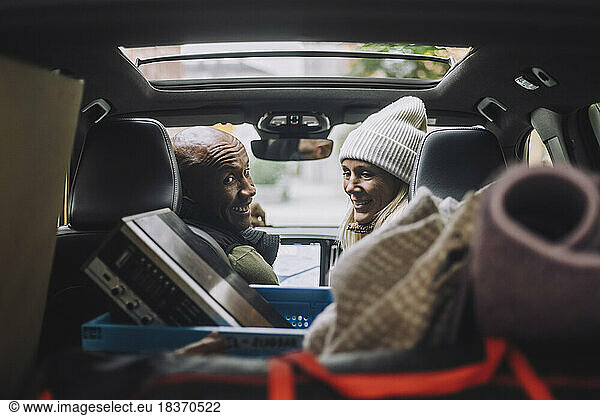 Happy mature couple looking back at luggage in car