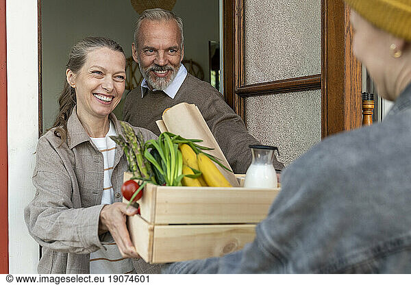 Happy mature couple receiving groceries via home delivery