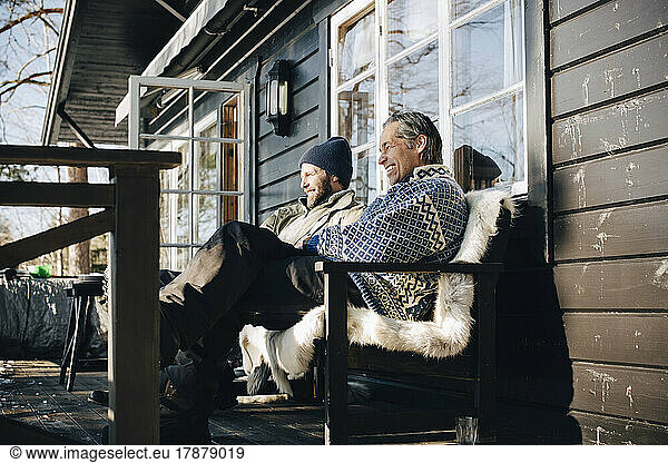 Happy mature friends sitting together at front porch in winter