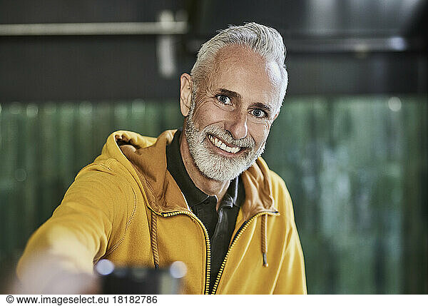 Happy mature man wearing yellow hooded shirt