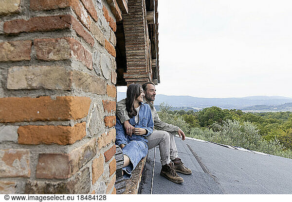 Happy mature woman and man sitting on rooftop