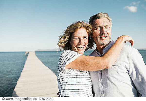 Happy mature woman and man standing on jetty