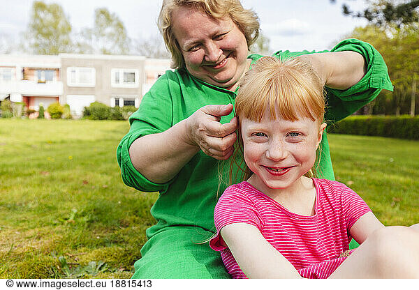 Happy mature woman combing hair of daughter