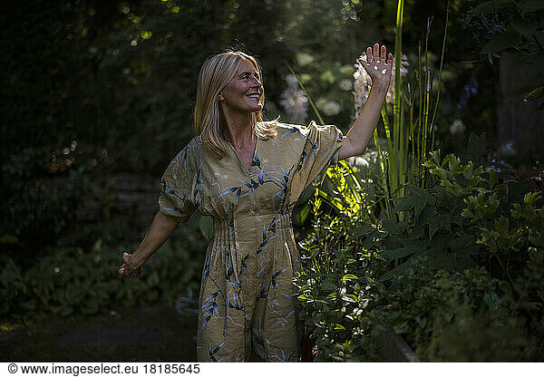 Happy mature woman enjoying amidst plants in garden