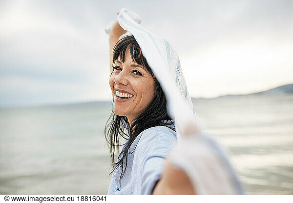 Happy mature woman enjoying with scarf at beach
