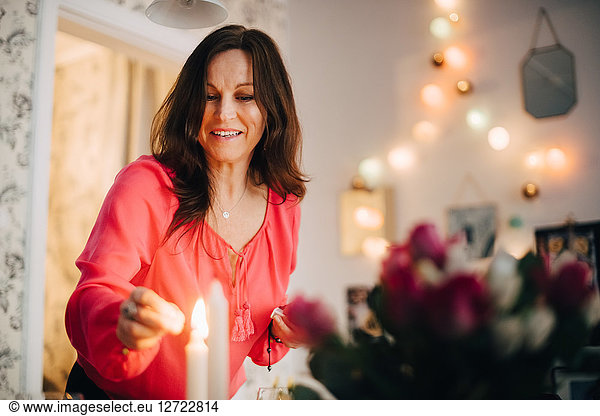 Happy mature woman igniting candle in party at home