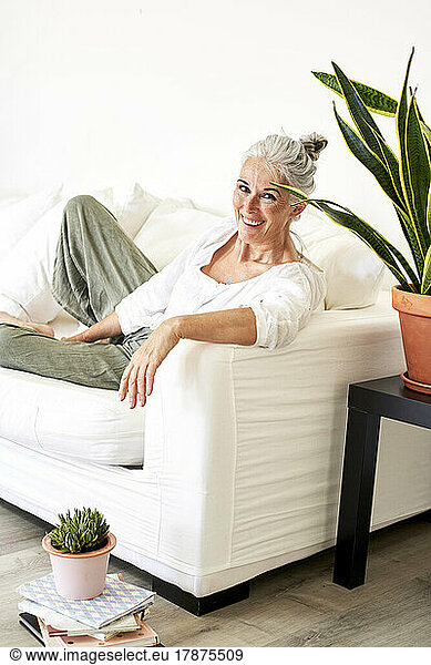 Happy mature woman leaning on armrest of sofa