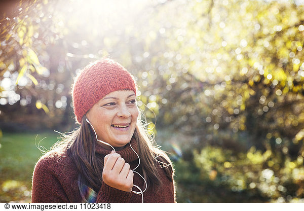 Happy mature woman listening music in forest