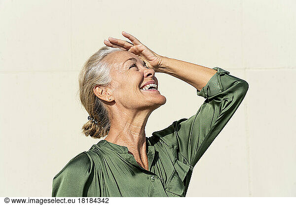 Happy mature woman shielding eyes on sunny day