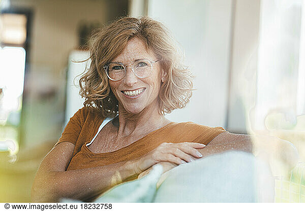 Happy mature woman sitting on sofa in living room