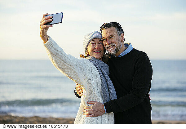 Happy mature woman taking selfie in front of sea