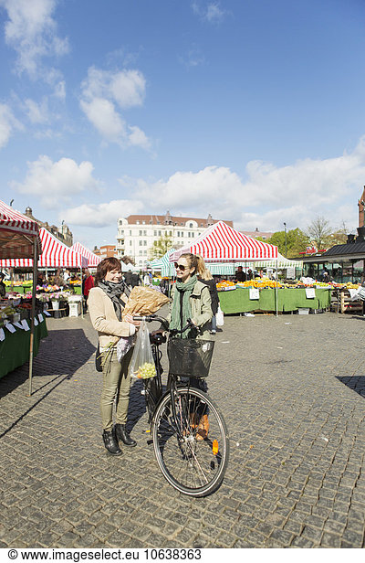 Happy mature woman with bicycle in market