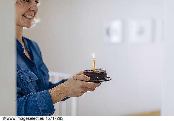 Happy mature woman with birthday cake at home
